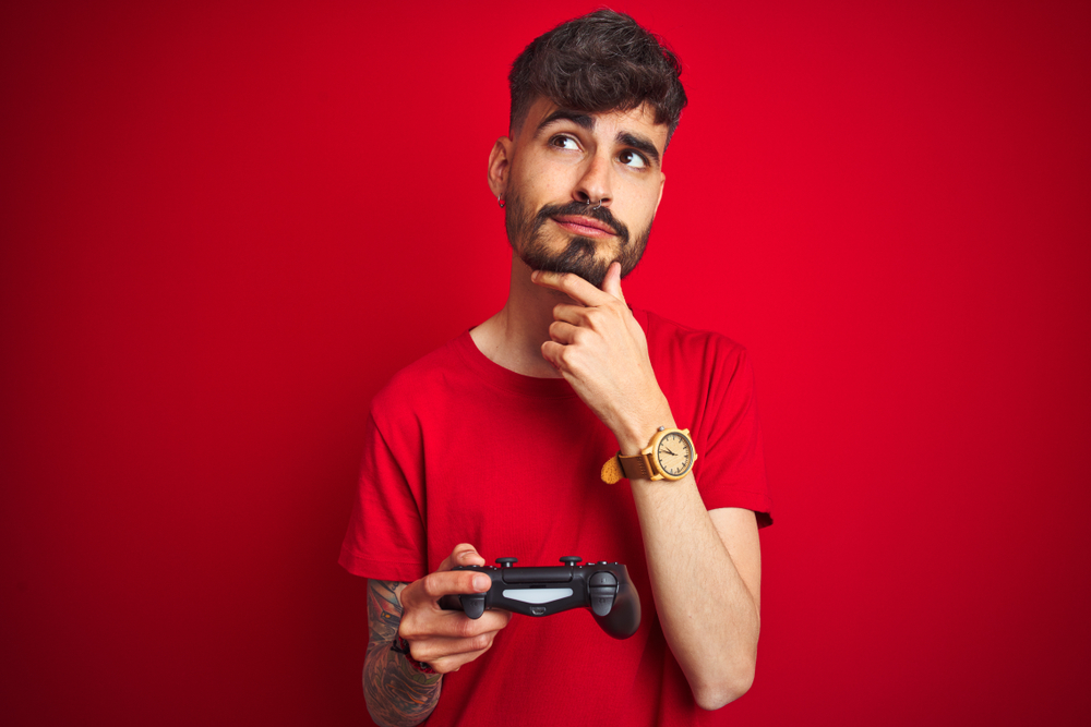 shutterstock 1499787998 - Young,Gamer,Man,With,Tattoo,Playing,Video,Game,Standing,Over